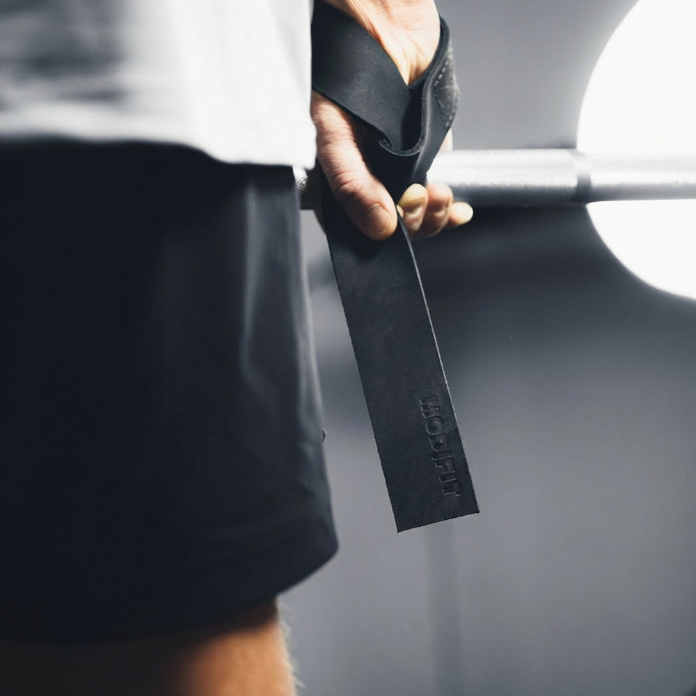 Black ModiFit leather lifting strap held beside a barbell