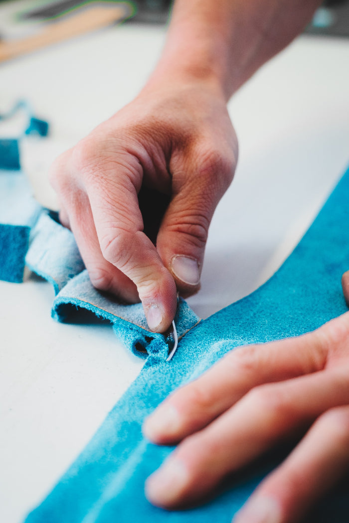 Trimming turquoise suede by hand during belt manufacture